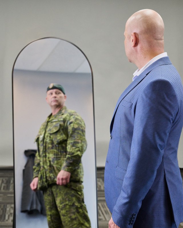 veteran in suit looking in mirror, imagining self in uniform